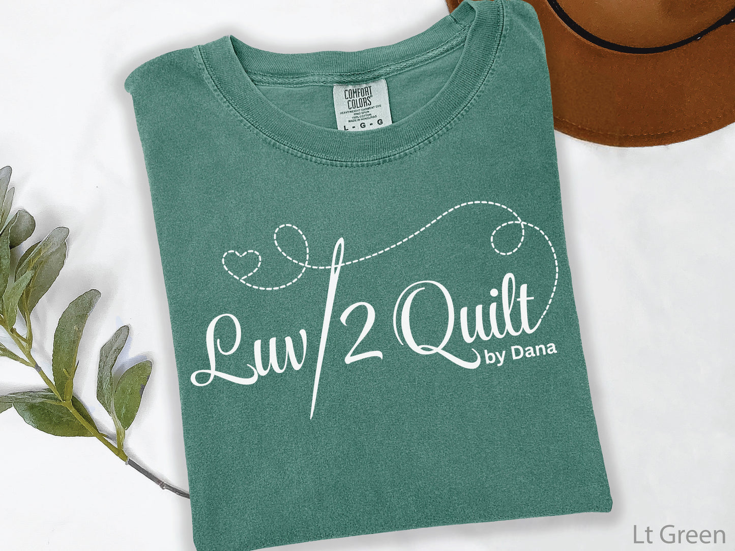 Official Luv2Quilt by Dana quilting-themed t-shirt featuring the Luv2Quilt logo with a sewing needle and stitched heart design, perfect for quilt classes, retreats, and everyday wear.