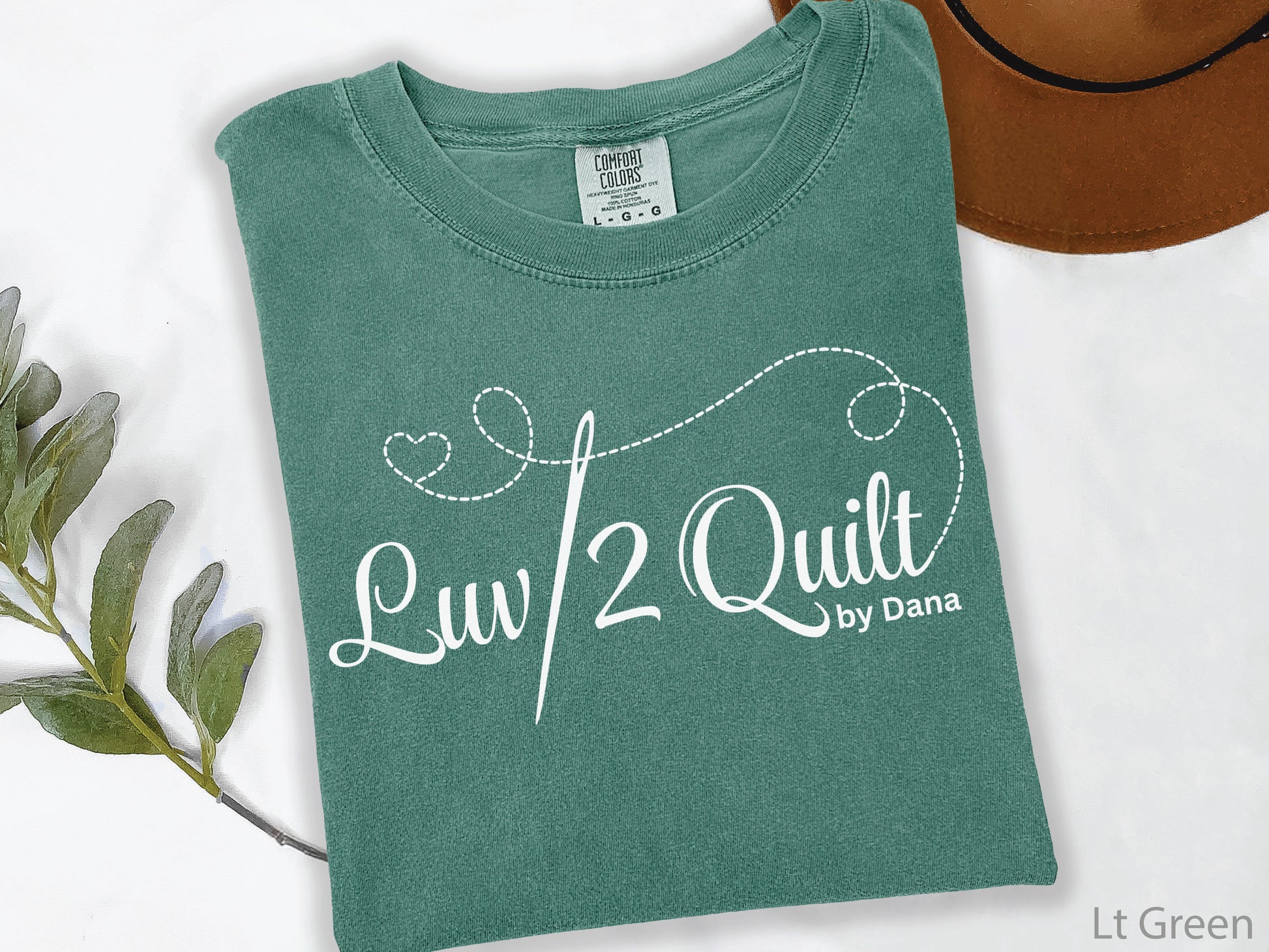 Official Luv2Quilt by Dana quilting-themed t-shirt featuring the Luv2Quilt logo with a sewing needle and stitched heart design, perfect for quilt classes, retreats, and everyday wear.