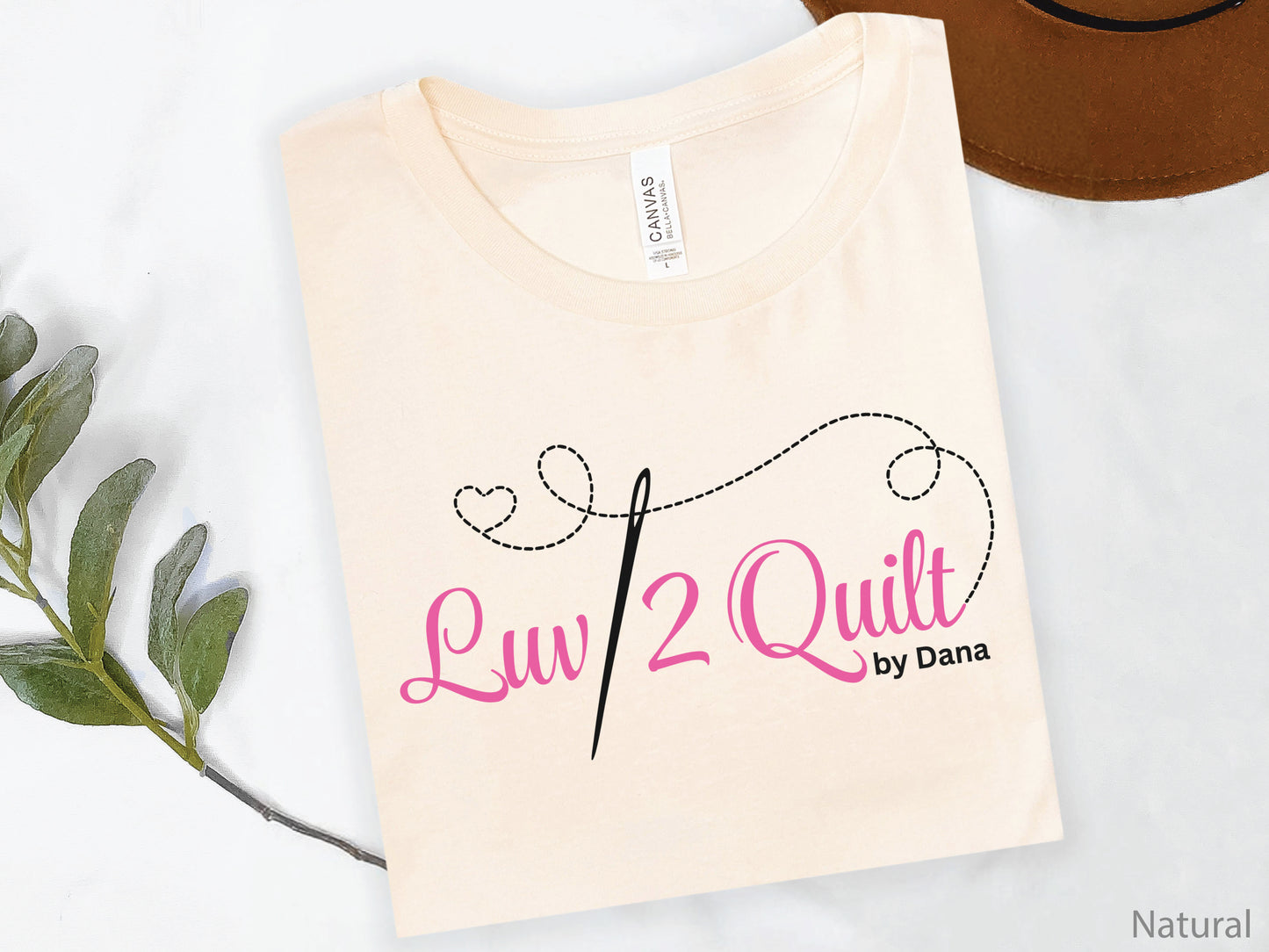 Official Luv2Quilt by Dana quilting-themed t-shirt featuring the Luv2Quilt logo with a sewing needle and stitched heart design, perfect for quilt classes, retreats, and everyday wear.