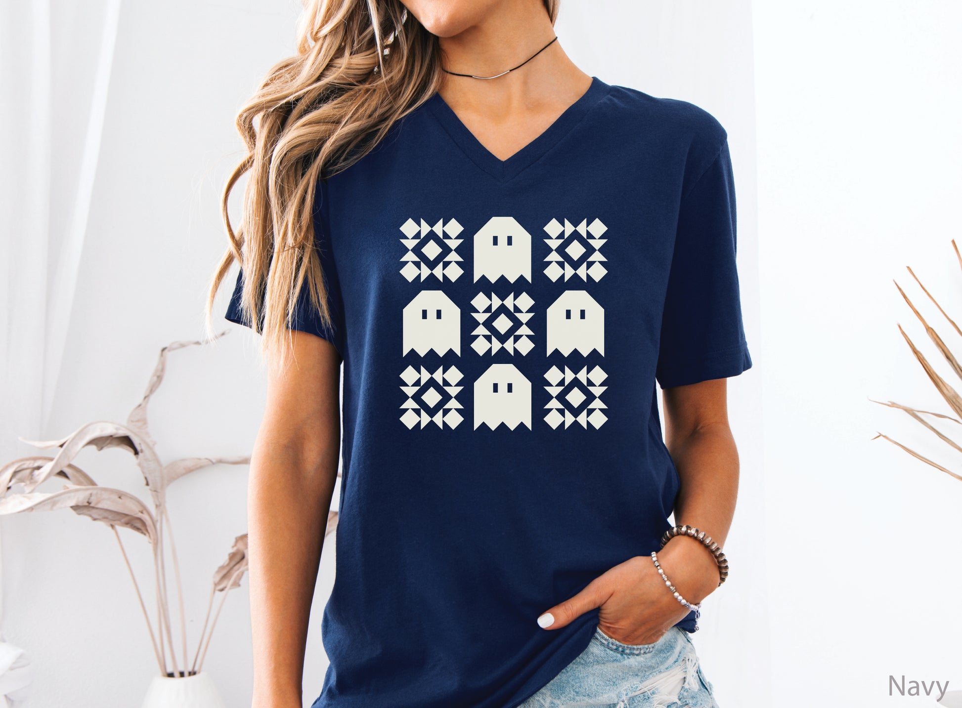 Soft Bella + Canva V-neck Halloween quilting t-shirt featuring a cream grid design with four spooky ghosts and five geometric quilt blocks. A customer favorite!