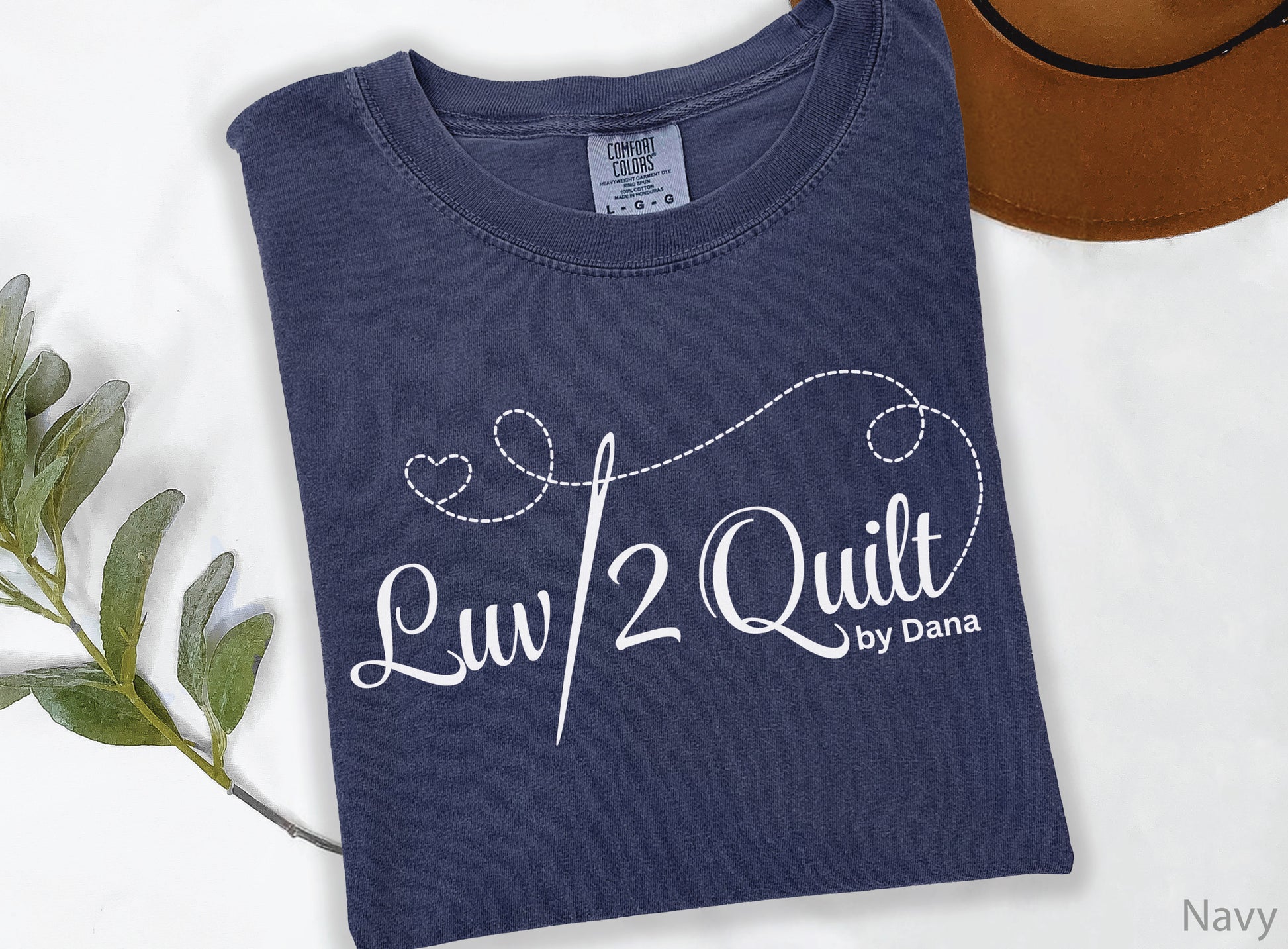 Official Luv2Quilt by Dana quilting-themed t-shirt featuring the Luv2Quilt logo with a sewing needle and stitched heart design, perfect for quilt classes, retreats, and everyday wear.