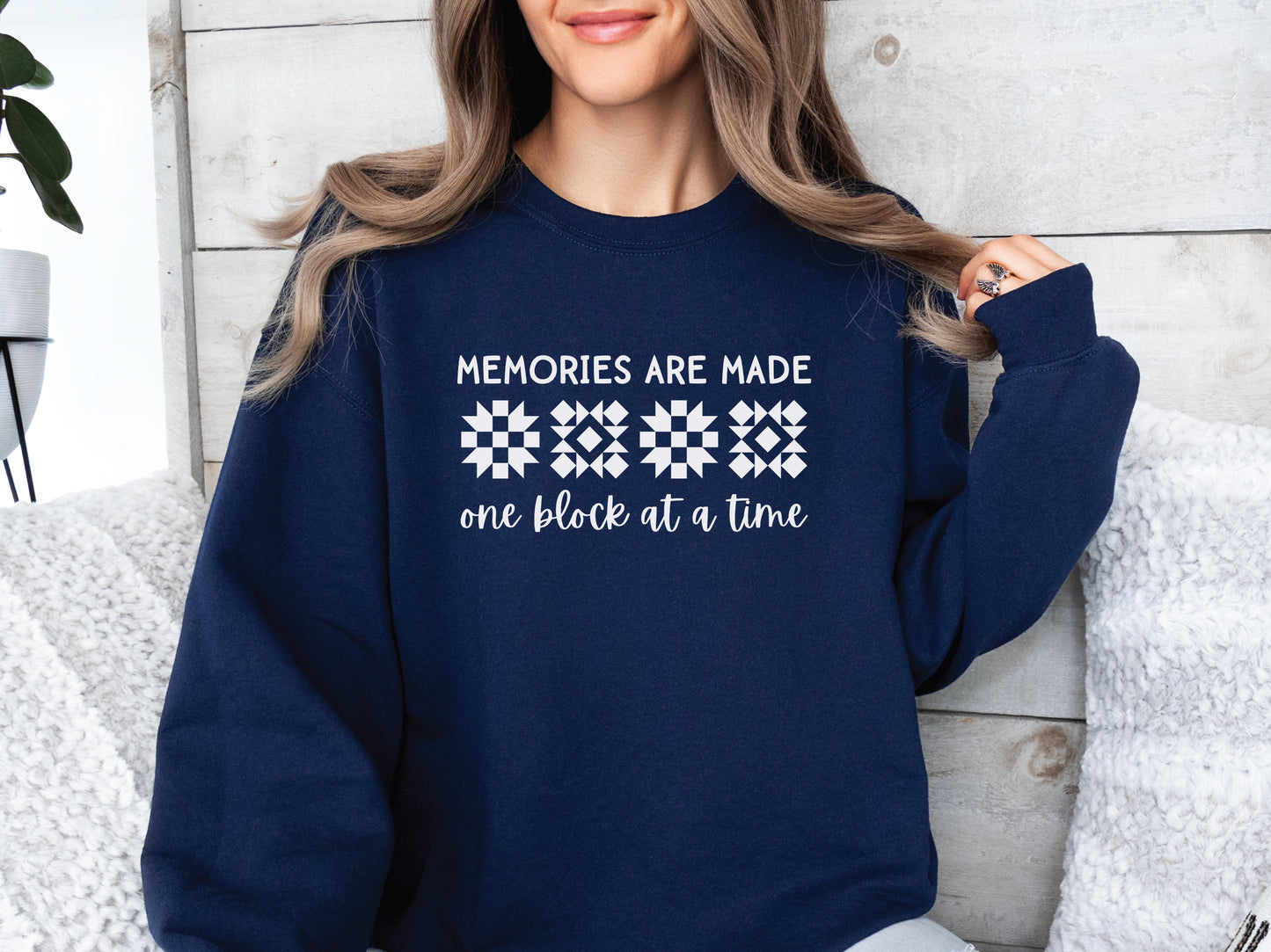 A long-sleeve quilt-themed sweatshirt from Bee Inspired Tees featuring the phrase “Memories Are Made One Block at a Time,” perfect for cozy sewing days, quilt retreats, or gifting to quilters who love celebrating their craft.