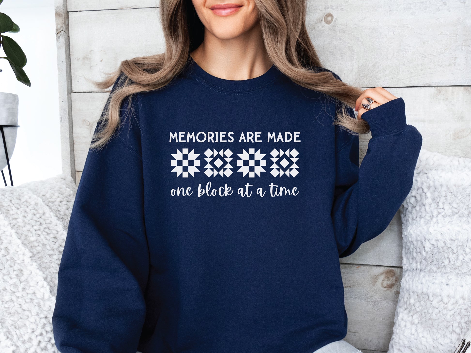 A long-sleeve quilt-themed sweatshirt from Bee Inspired Tees featuring the phrase “Memories Are Made One Block at a Time,” perfect for cozy sewing days, quilt retreats, or gifting to quilters who love celebrating their craft.