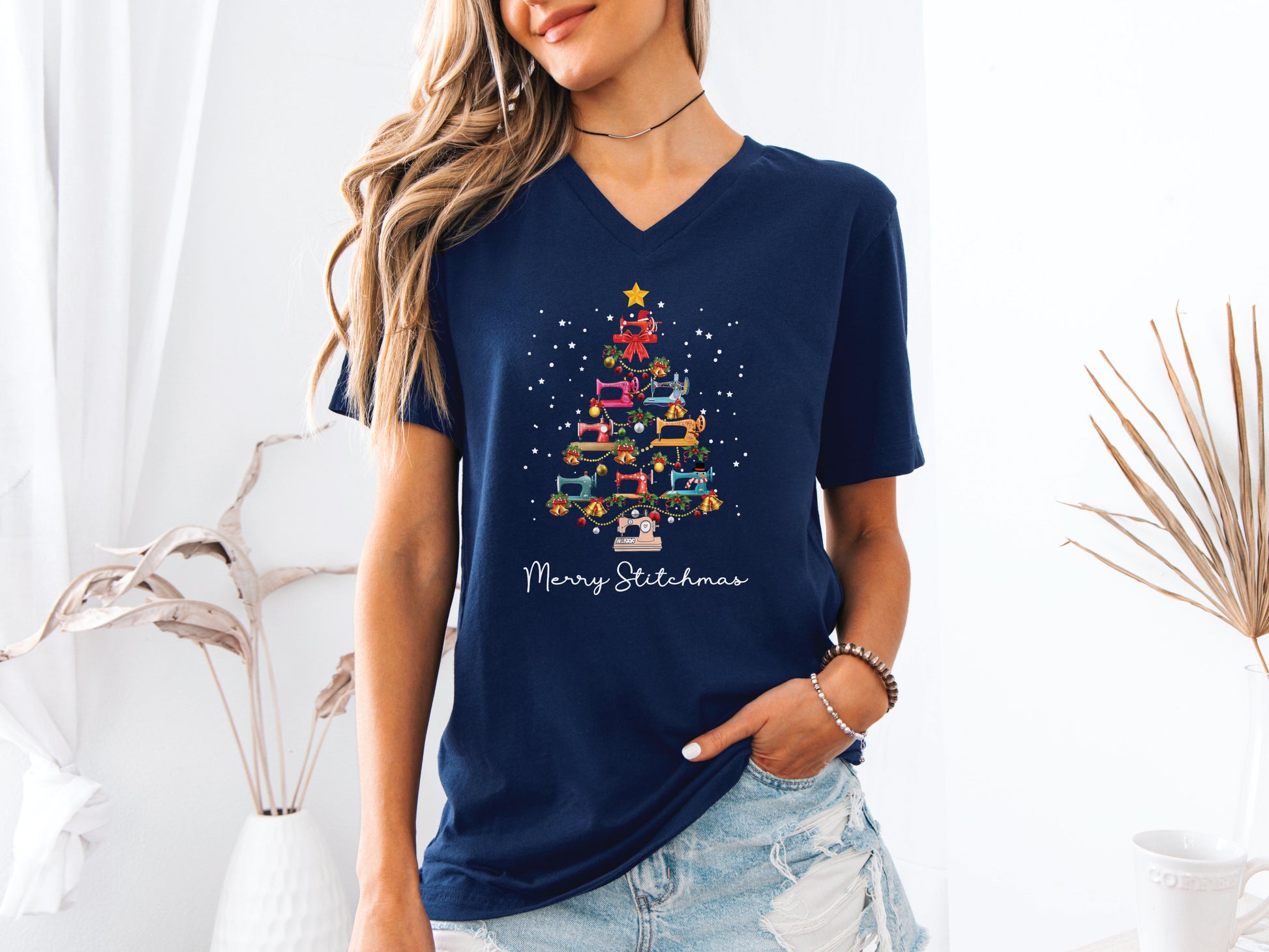 Festive Christmas tree made of colorful sewing machines with the phrase “Merry Stitchmas” on a V-neck t-shirt, a fun holiday gift for quilters and sewing enthusiasts.