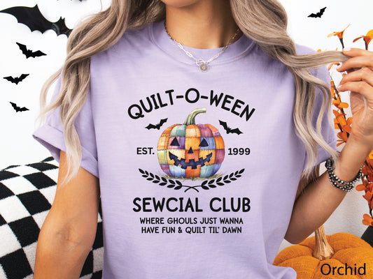 Quilt-O-Ween Sewcial Club shirt from Bee Inspired Tees, designed in Orchid with a colorful patchwork jack-o’-lantern, bats, and playful Halloween typography—perfect gift for quilters.