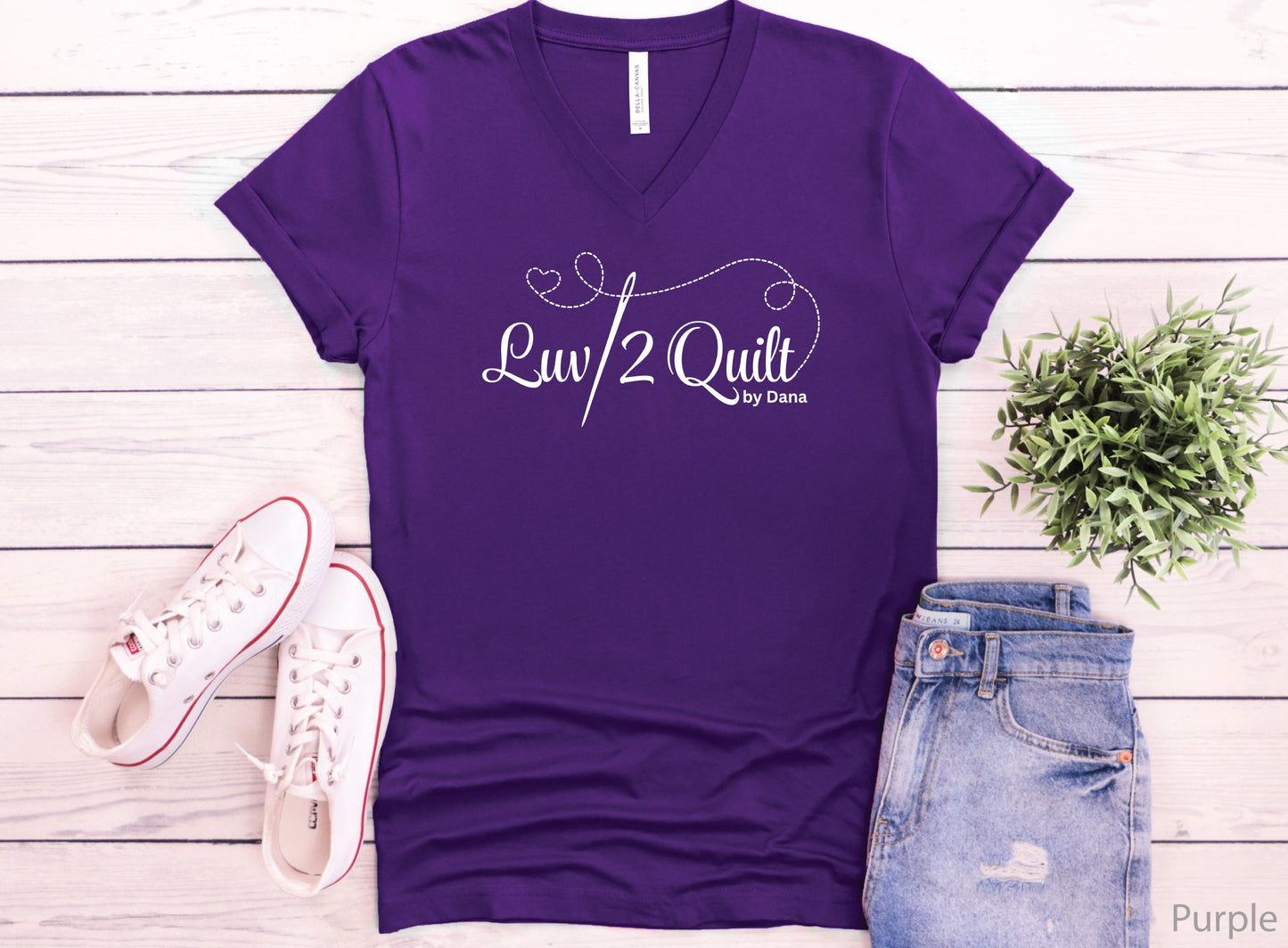 Official Luv2Quilt by Dana quilting-themed t-shirt featuring the Luv2Quilt logo with a sewing needle and stitched heart design, perfect for quilt classes, retreats, and everyday wear.