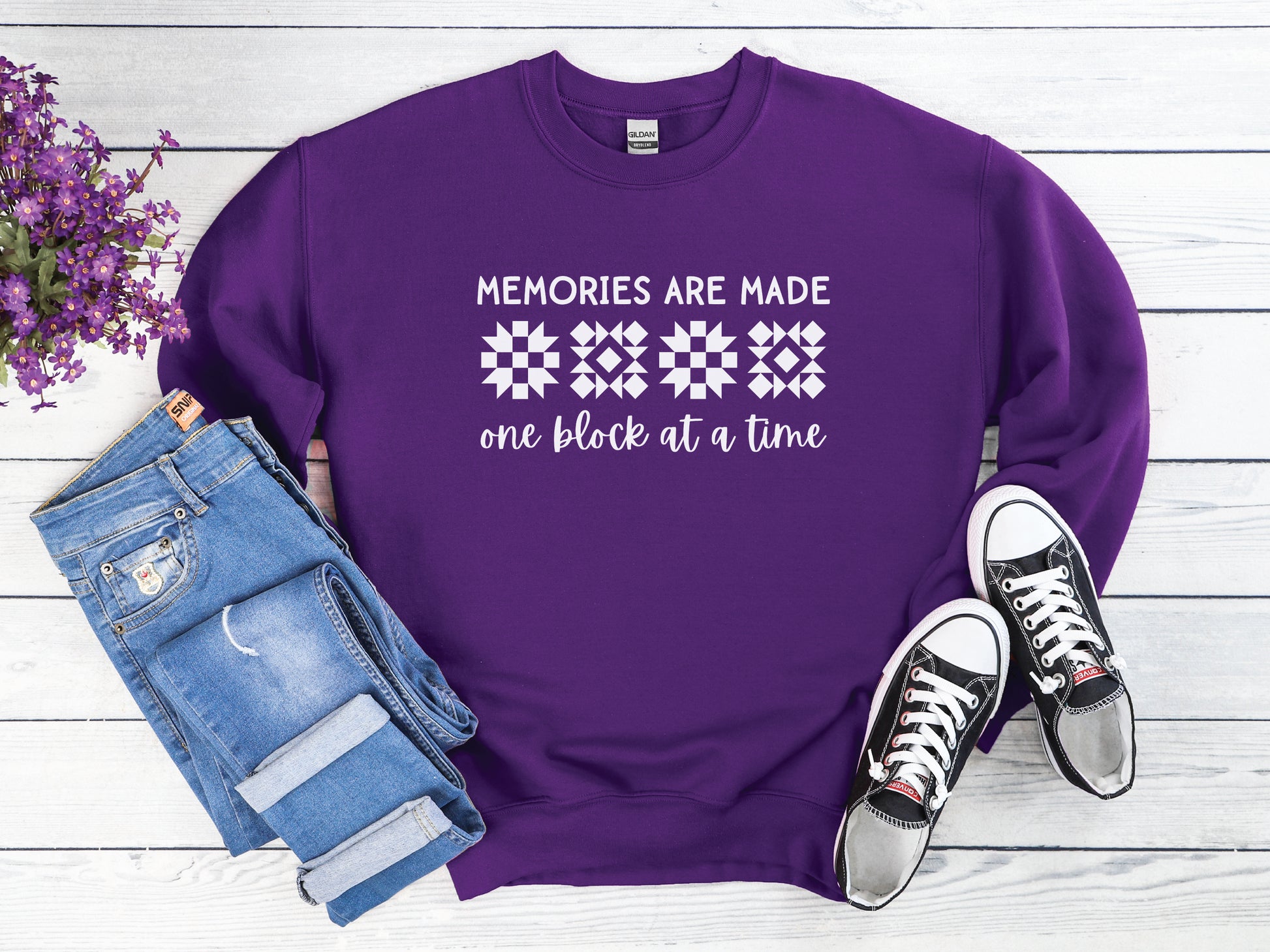 A long-sleeve quilt-themed sweatshirt from Bee Inspired Tees featuring the phrase “Memories Are Made One Block at a Time,” perfect for cozy sewing days, quilt retreats, or gifting to quilters who love celebrating their craft.