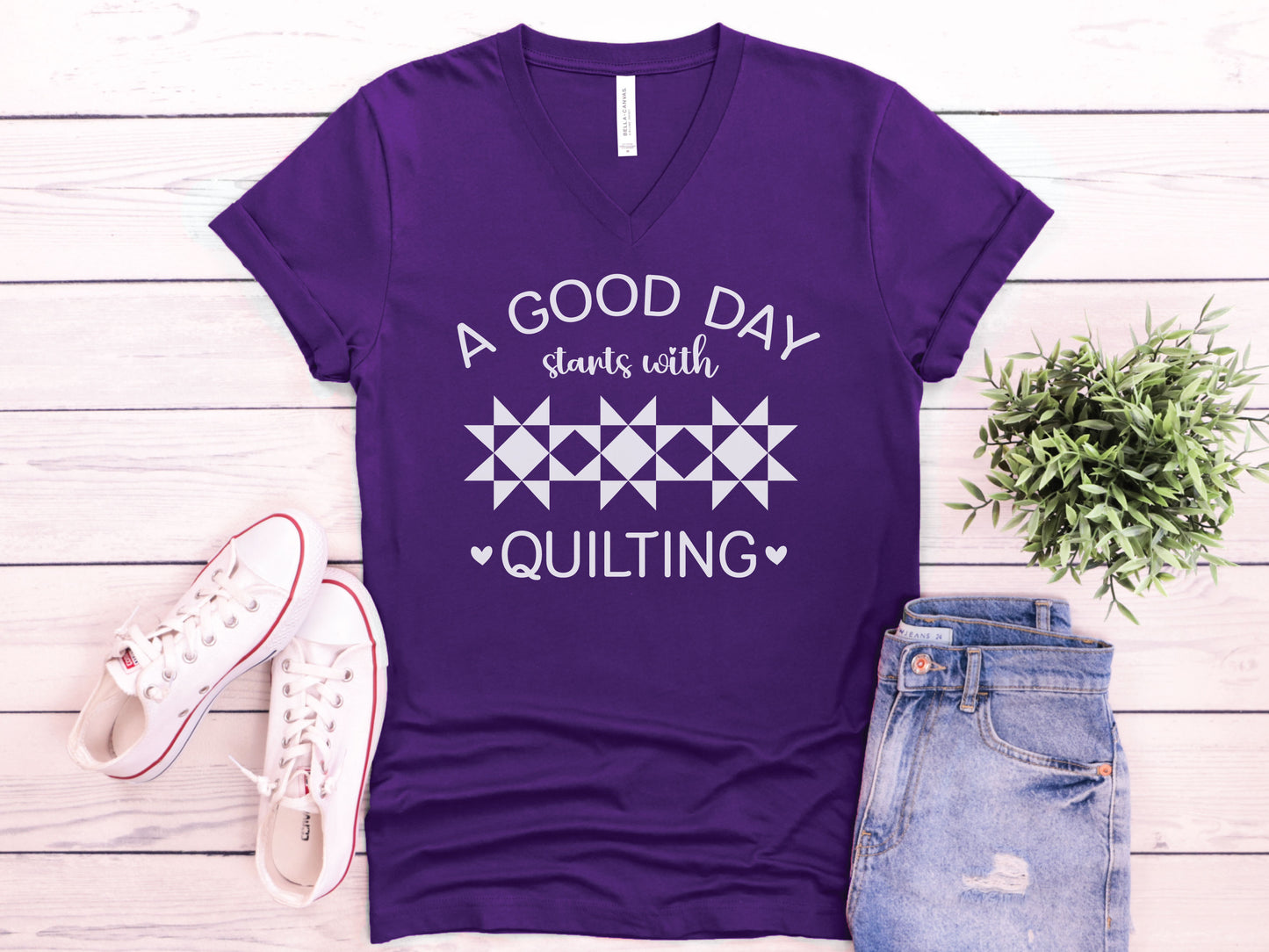 A quilt-themed v-neck  t-shirt featuring a vintage-style sewing machine, quilt block icons, and the verse “She works with her hands in delight – Proverbs 31:13.” 