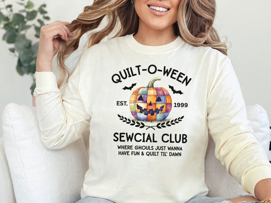 Quilt-O-Ween Sewcial Club long sleeve Ivory colored shirt from Bee Inspired Tees, featuring a colorful patchwork jack-o’-lantern, bats, and playful Halloween typography—fun gift for quilters.