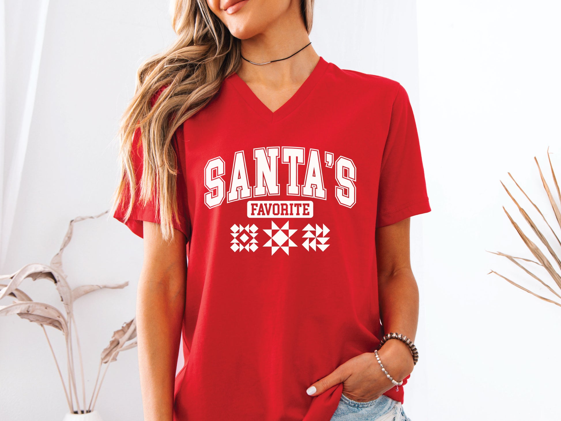 Festive V-Neck short sleeve t-shirt with the phrase “Santa’s Favorite” in bold varsity letters and three quilt block designs, styled for quilters who love Christmas and handmade gifts.