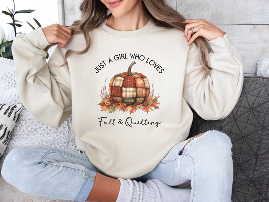 Beige (Sand) colored sweatshirt from Bee Inspired Tees with the phrase “Just a Girl Who Loves Fall & Quilting,” featuring a plaid pumpkin surrounded by autumn leaves. Perfect fall gift for quilters and ideal for quilt retreats or sewing days.