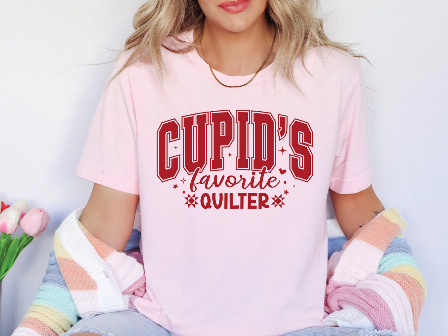 Valentine’s Day quilting t-shirt with “Cupid’s Favorite Quilter” phrase in varsity-style lettering and quilt-inspired details, perfect for quilters.