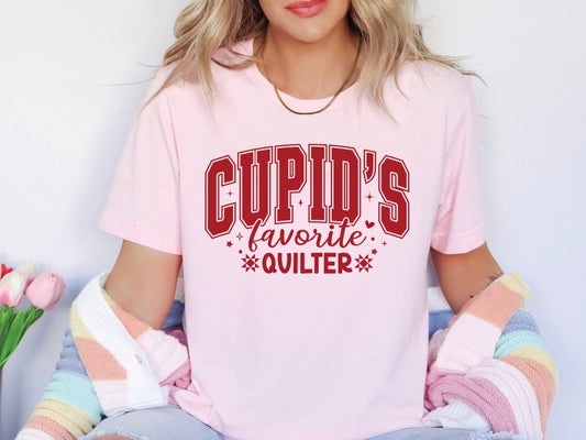 Valentine’s Day quilting t-shirt with “Cupid’s Favorite Quilter” phrase in varsity-style lettering and quilt-inspired details, perfect for quilters.