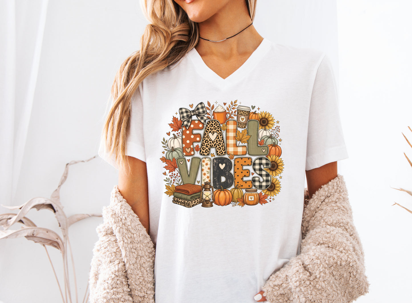 Fall Vibes t-shirt design with patchwork-style lettering, pumpkins, sunflowers, fall leaves, cozy drinks, lantern, candle, and folded blankets.