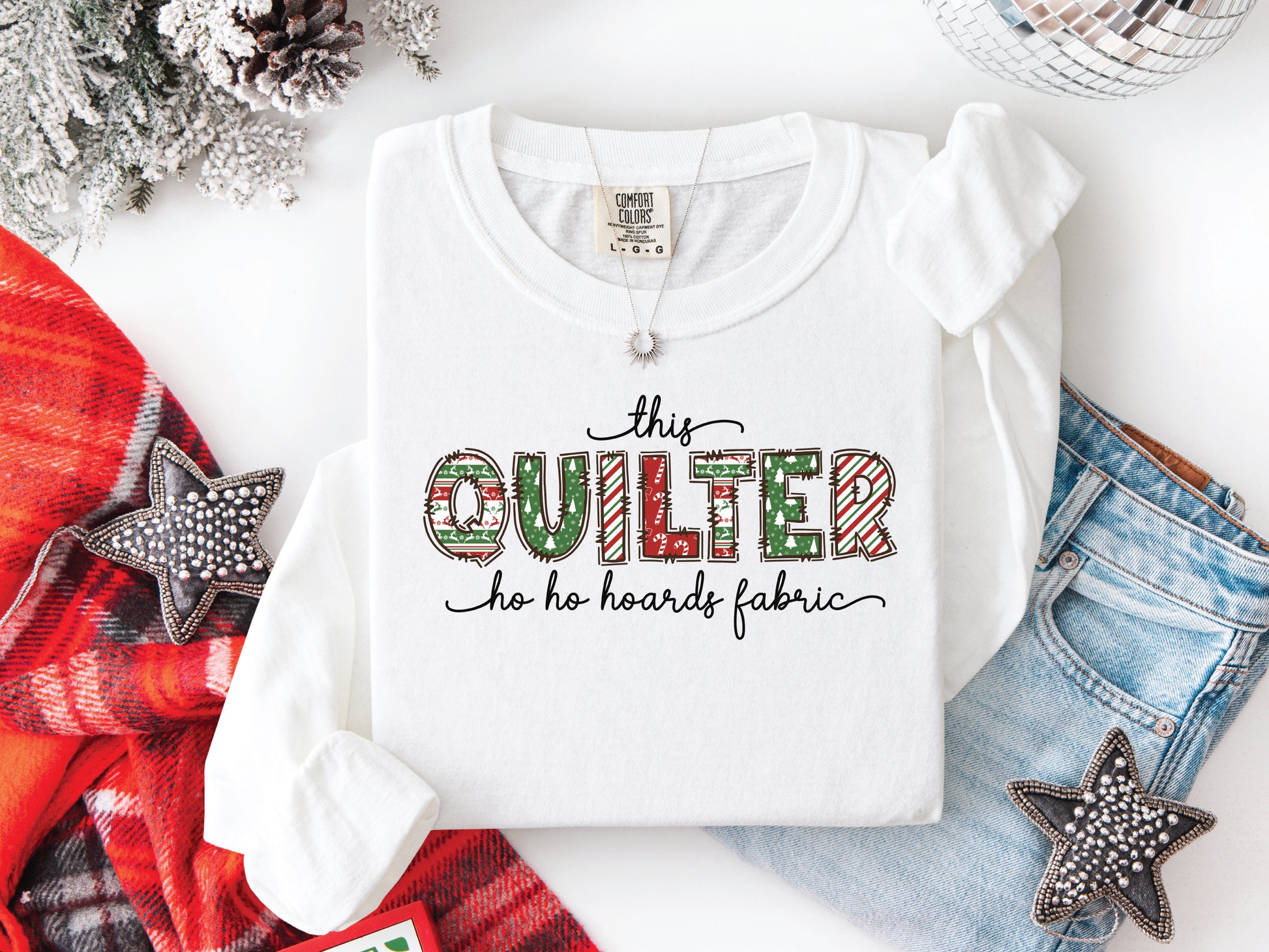 This Quilter Ho Ho Hoards Fabric long sleeve t-shirt with red and green patchwork lettering, a funny Christmas shirt for quilters who love fabric, sewing, and holiday cheer.