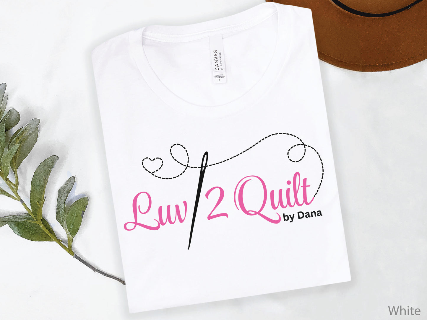 Official Luv2Quilt by Dana quilting-themed t-shirt featuring the Luv2Quilt logo with a sewing needle and stitched heart design, perfect for quilt classes, retreats, and everyday wear.