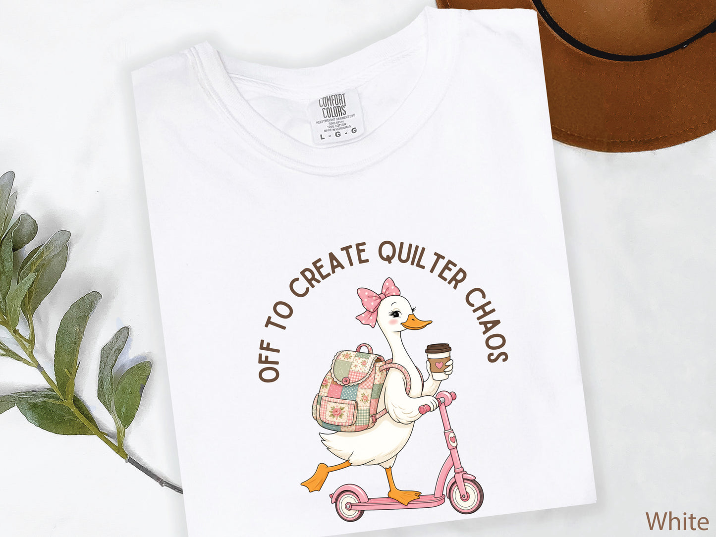 Funny quilting t-shirt featuring a goose riding a pink scooter with coffee and a patchwork backpack, paired with the saying “Off To Create Quilter Chaos.” Perfect for quilters, sewists, quilt retreats, and fabric lovers.