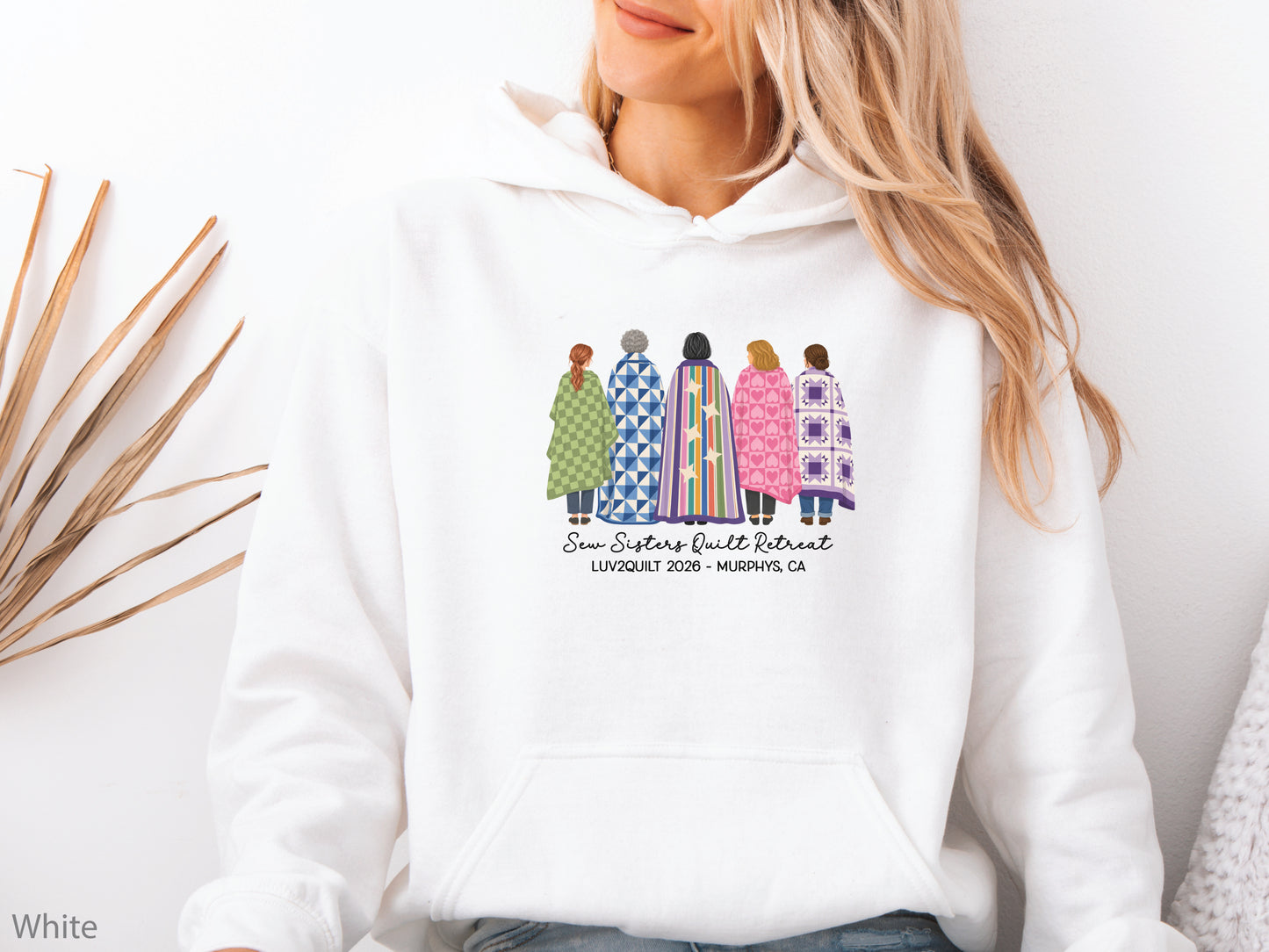 Sew Sisters Quilt Retreat hoodie sweatshirt featuring five quilters wrapped in colorful quilts, personalized for the LUV2QUILT 2026 retreat in Murphys, CA.
