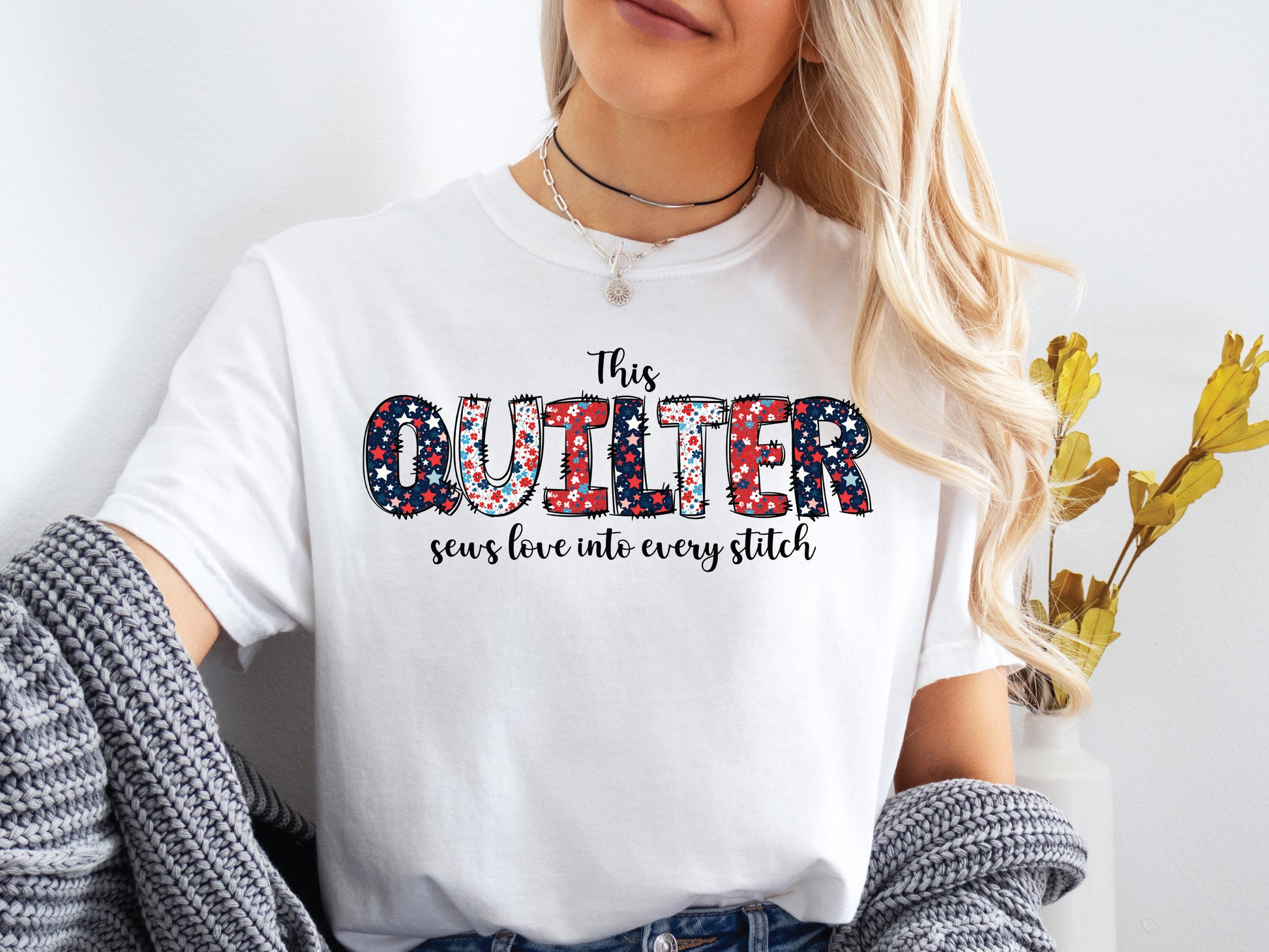 Patriotic quilting t-shirt with the phrase “This Quilter Sews Love Into Every Stitch” in red, white, and blue patchwork lettering, perfect for celebrating America’s 250th Anniversary.