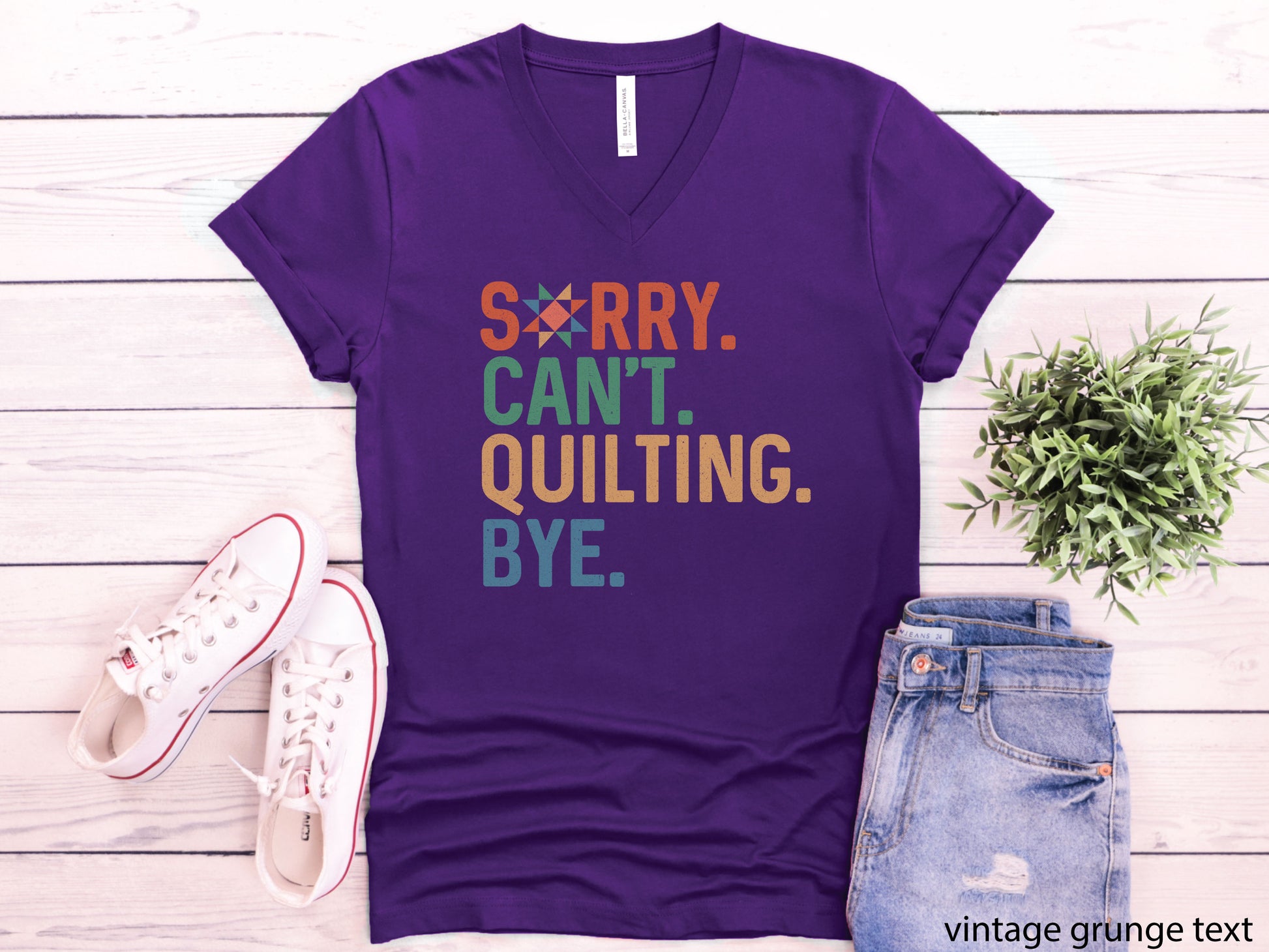 Funny “Sorry, Can’t. Quilting. Bye.” V-neck T-shirt with distressed vintage-style lettering, shown on a purple shirt — a humorous gift for sewing and quilting lovers.