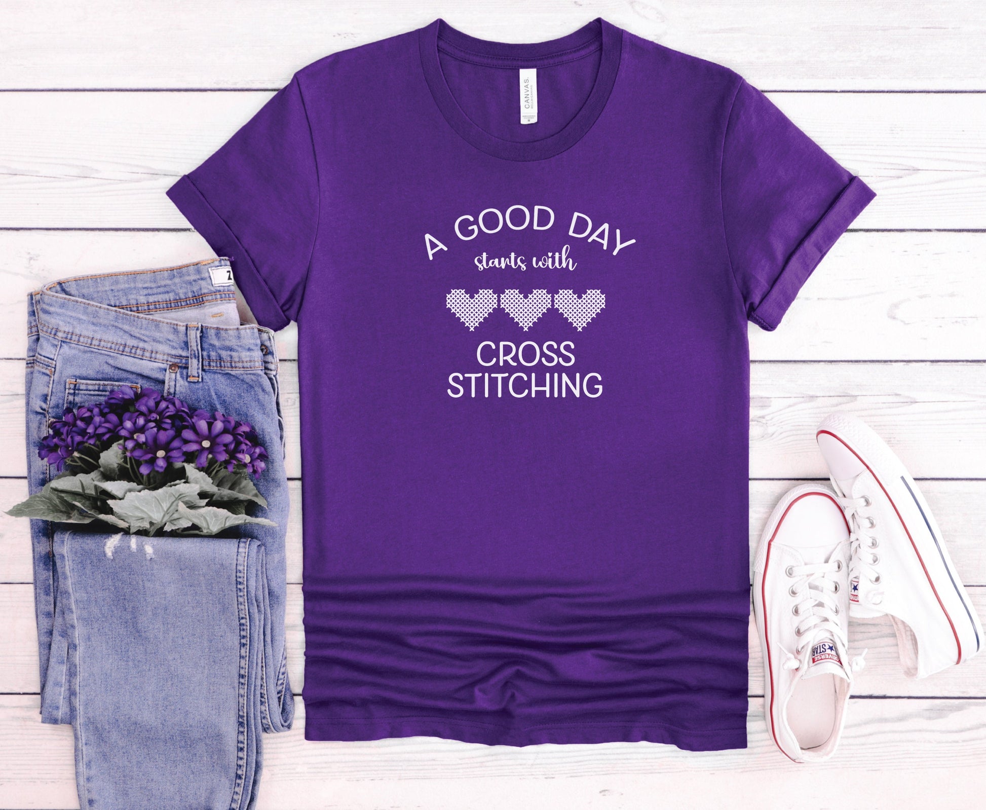 A Good Day Starts With Cross Stitching shirt, with 3 hearts printed on a purple shirt.