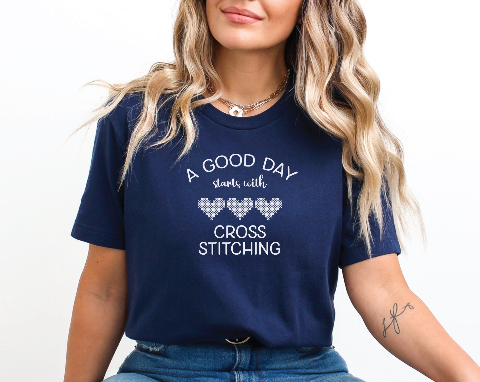 A Good Day Starts With Cross Stitching shirt, with 3 hearts printed on a navy shirt.